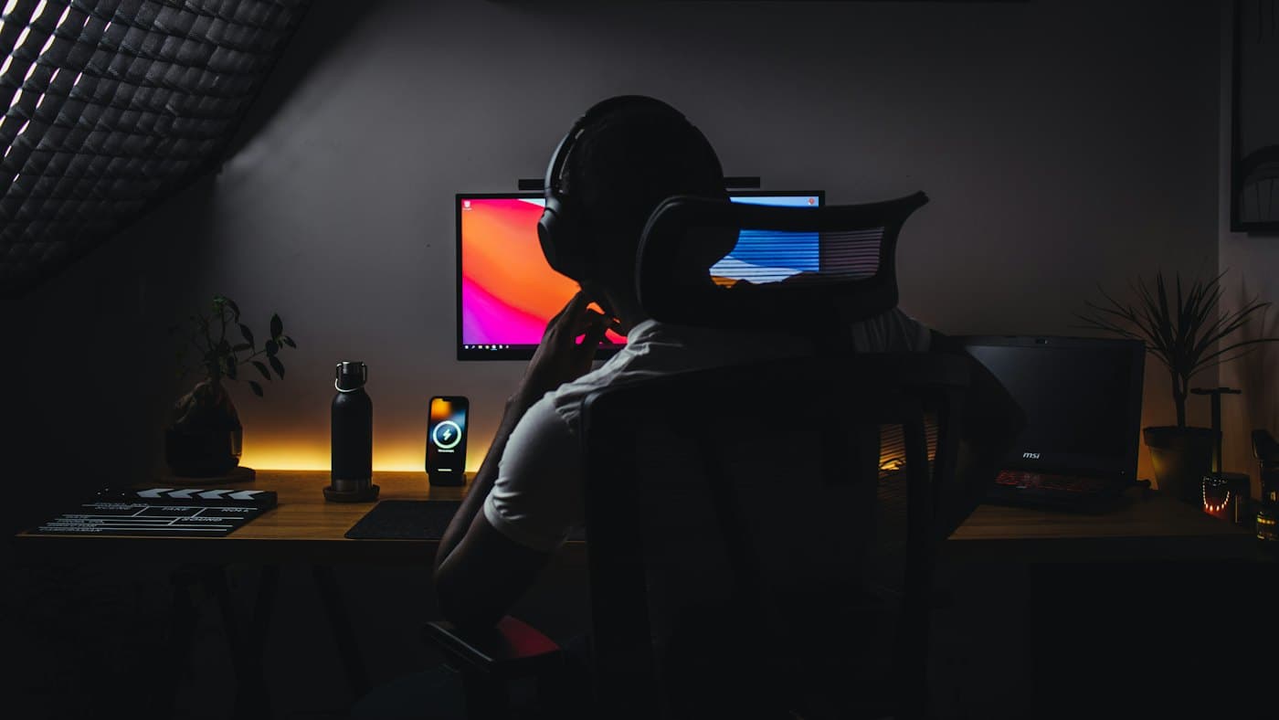 A person wearing headphones writing at a computer